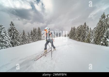 Enfant grimpant sur des skis dans des peaux de phoque buvant de l'eau froide Banque D'Images