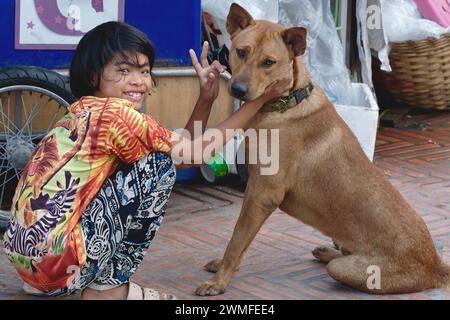 Une jeune fille thaïlandaise, sa famille vivant dans un abri routier de make-shift à Bangkok, Asie du Sud-est, Thaïlande, avec par chien de compagnie bien-aimé Banque D'Images