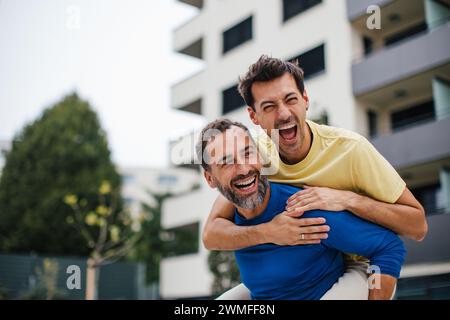 Meilleurs amis jouant du sport à l'extérieur, s'amusant. But de célébration, porter ami sur le dos, piggyback. Concept d'amitié masculine, bromance. Banque D'Images