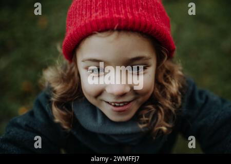 Portrait de petite fille en bonnet tricoté rouge. Fille de capot d'équitation rouge ou petite redcap ressemblant. Banque D'Images