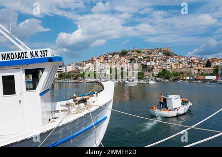 Un bateau au premier plan avec une vue sur une ville à flanc de colline au bord de la mer sous un ciel partiellement nuageux, vieille ville, Kavala, Dimos Kavalas, Macédoine orientale Banque D'Images