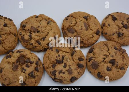 Bonbons, délicieux biscuits aux pépites de chocolat avec de gros morceaux de lait et de chocolat noir disposés sur un fond blanc. Banque D'Images