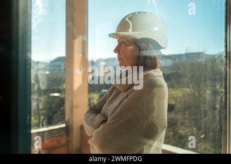 Portrait de femme architecte sur le chantier de construction vu à travers la fenêtre sale, mise au point sélective Banque D'Images