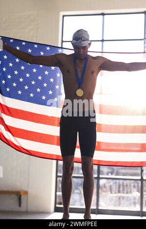 Fier jeune athlète masculin biracial nageur affiche une médaille d'or, avec espace de copie Banque D'Images