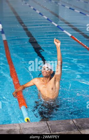 Un jeune nageur athlète masculin biracial célèbre la victoire dans une piscine Banque D'Images