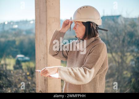 Femme architecte prenant des notes et des remarques lors de l'inspection du site de construction, focalisation sélective Banque D'Images