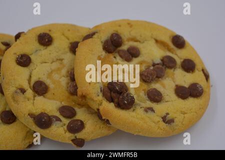 Bonbons, délicieux, grands biscuits avec de petits morceaux de chocolat au lait disposés sur un fond blanc. Banque D'Images