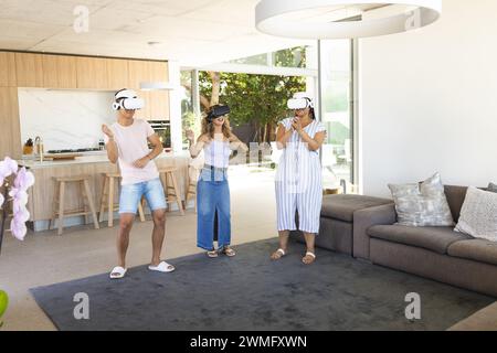 Un jeune homme asiatique et deux jeunes femmes biraciales apprécient la réalité virtuelle à la maison Banque D'Images