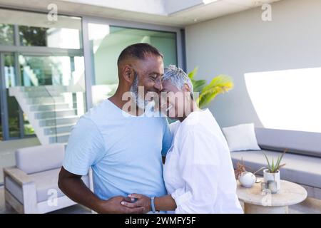 Couple biracial senior partage un moment tendre à la maison Banque D'Images