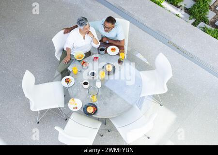Couple biracial senior profite du petit déjeuner à l'extérieur, avec espace de copie Banque D'Images