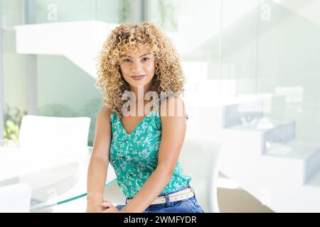 Une jeune femme biraciale sourit dans un bureau lumineux Banque D'Images