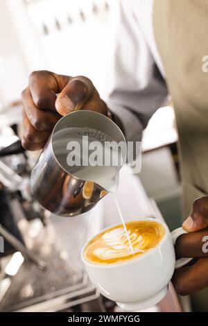 Un barista afro-américain fabrique un latte dans un café Banque D'Images