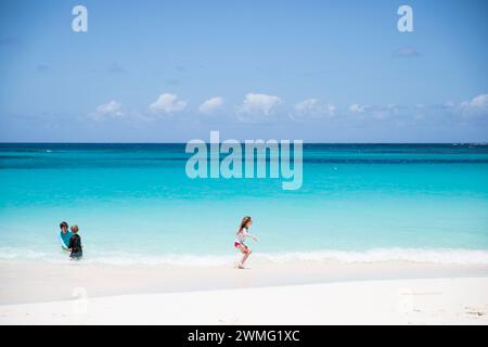 Vue large des frères et sœurs jouant ensemble sur Shoal Bay Beach à Anguilla Banque D'Images