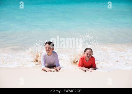 Frère et soeur jouent dans les vagues sur Caribbean Beach Banque D'Images