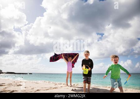 Trois frères et sœurs heureux jouent ensemble à Cloudy Caribbean Beach Banque D'Images