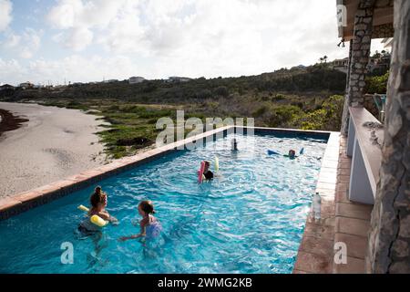 Famille nage ensemble dans la piscine à débordement en vacances dans les Caraïbes Banque D'Images