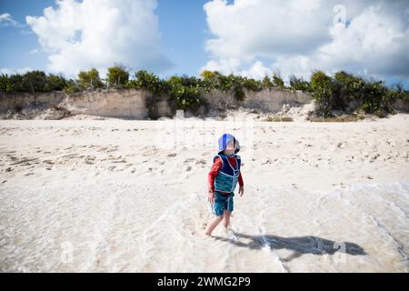 Tout-petit garçon avec une grande ombre joue sur la plage à Anguilla Banque D'Images