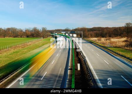 Photo longue exposition d'une autoroute très fréquentée avec silhouettes de voitures circulant sur route. Trafic sur autoroute avec des voitures floues en mouvement Banque D'Images