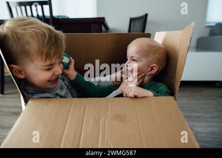 Gros plan de deux jeunes garçons jouant farouchement dans une boîte en carton Banque D'Images