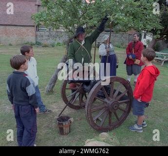 Fourrage à canon ? De jeunes garçons du XXIe siècle rencontrent un combattant costumé de la Sealed Knot Society du XVIIe siècle avec canon au Fleece Inn du National Trust, Bretforton, Worcestershire, lors d'une manifestation extérieure de la reconstitution de la guerre civile anglaise. Banque D'Images