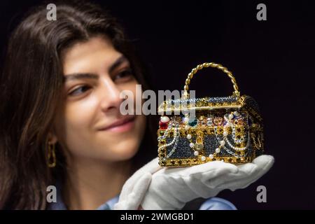 Londres, Royaume-Uni. 26 février 2024. Un membre du personnel avec une pochette Judith Leiber : Gold 'Sunken Treasure Chest', 2022, (est. £600 - £800) à un aperçu de Bonhams à venir sacs à main de créateurs et vente de mode. Les sacs à main de luxe et les modèles de prêt-à-porter seront vendus aux enchères dans les galeries Bonhams Knightsbridge le 28 février. Credit : Stephen Chung / Alamy Live News Banque D'Images