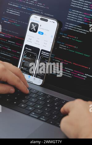 New York, États-Unis - 23 février 2024 : Code pour la nouvelle application X dans l'écran d'ordinateur portable avec les mains sur le clavier Banque D'Images