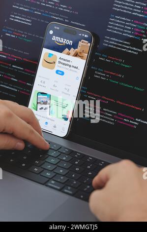 New York, États-Unis - 23 février 2024 : Code pour la nouvelle application Amazon shopping dans l'écran d'ordinateur portable avec les mains sur le clavier Banque D'Images