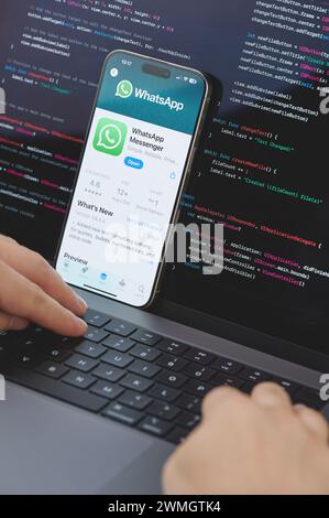 New York, États-Unis - 23 février 2024 : Code pour la nouvelle application Whatsapp dans l'écran d'ordinateur portable avec les mains sur le clavier Banque D'Images
