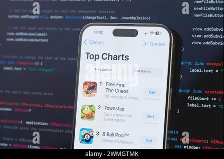 New York, États-Unis - 23 février 2024 : meilleurs jeux de classements sur l'écran de l'iphone en arrière-plan de programmation de code flou Banque D'Images
