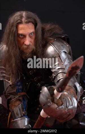 Performance pour touristes. Composition verticale. Portrait d'un homme charismatique habillé en chevalier médiéval avec une lance lors d'un reconstitutionnisme historique Banque D'Images