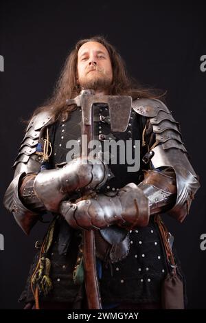 Composition verticale. Portrait d'un chevalier médiéval aux cheveux longs avec une hache et portant des poignées de fer. Banque D'Images