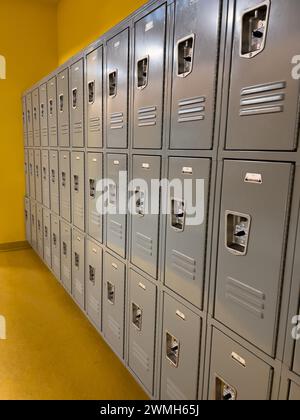 Rangées de casiers de l'école grise alignées contre un mur jaune Banque D'Images