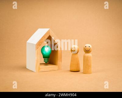 Durabilité à la maison, responsabilité environnementale, concepts de famille éco. Ampoule verte 3d avec symbole de soins de la terre dans une petite maison blanche avec Happy co Banque D'Images