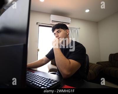 Portrait réfléchi d’un jeune homme engagé dans son espace de travail, analysant les données et planifiant les stratégies d’affaires Banque D'Images