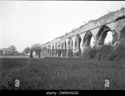 Un groupe d'hommes et de femmes à côté des ruines d'un pont de l'empire romain dans le sud-est FR. Début du XXe siècle. Vieille photographie restaurée à partir de plaque de verre. Banque D'Images