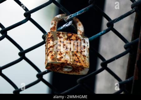 vieux cadenas colorés rouillés verrouillés sur un mur de filet Banque D'Images
