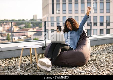 Portrait d'une femme africaine buvant du café tout en levant la main vers le haut. Banque D'Images