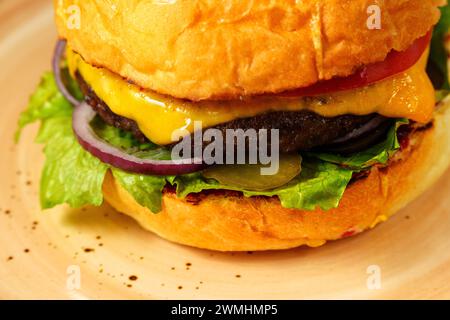 Cheeseburger garni de laitue et de différentes garnitures placées sur une assiette, prêt à être dégusté. Banque D'Images