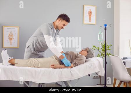 Patient âgé malade allongé sur le canapé à l'hôpital recevant une perfusion intraveineuse. Banque D'Images
