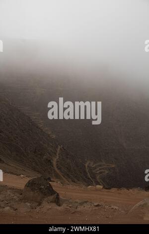 Photo verticale de vue de dessus de routes de montagne brunes avec des rochers et du brouillard sur le dessus Banque D'Images
