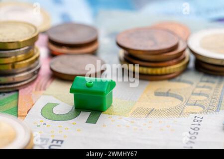 Petite maison jouet par piles de pièces de monnaie Banque D'Images