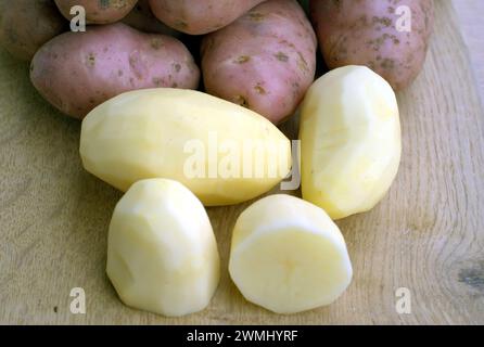 Beaucoup de pommes de terre pelées et de pommes de terre non pelées sur le bureau de cuisine dans le processus de cuisson des aliments vue rapprochée Banque D'Images