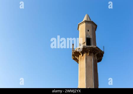 Ancien minaret en grès détruit d'une mosquée sur fond de ciel bleu cristal dans Al Jazirah Al Hamra ville hantée aux Émirats arabes Unis. Banque D'Images