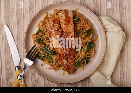 Poisson blanc poêlé sur un lit de nouilles aux épinards. Banque D'Images