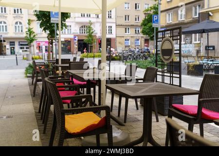 Une rangée de tables et de chaises avec parasols au-dessus de la tête dans une salle à manger extérieure. Banque D'Images