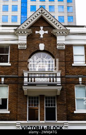 Une photo en gros plan d'un bâtiment de style victorien sur Pender Street, avec son mur de briques brun foncé contrastant et ses éléments peints en blanc. Banque D'Images