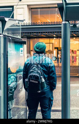 Vancouver, Canada - 21 février 2024 : un homme de grande taille portant un dastar attend le bus à un arrêt sur Granville Street, entre deux abris de bus. Banque D'Images