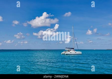 Bateau à voile blanc voyageant dans la mer bleue des Maldives sur une journée d'été ensoleillée au milieu de nulle part. Mer tropicale et voilier. Pas de voiles Banque D'Images