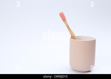 Brosse à dents en bambou dans un support isolé sur blanc Banque D'Images