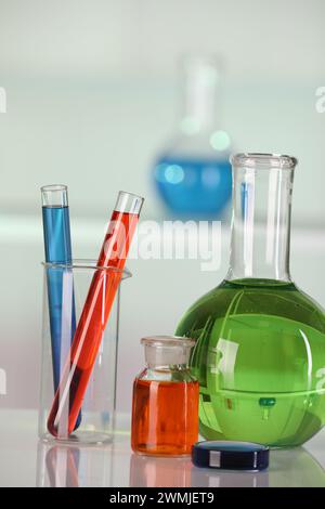 Analyse de laboratoire. Verrerie différente avec des liquides sur la table blanche sur fond flou Banque D'Images